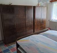 A bedroom in a family house with a bed, wardrobes, and a carpet with a colorful pattern.