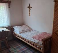 A simple room in a family house with wooden furniture, a carpet, and a cross on the wall.