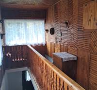 A hallway in a family house with wooden paneling and carved railing.