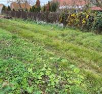 A residential plot in Tvrdošovce bordered by a fence, with a grassy surface and neighboring houses.