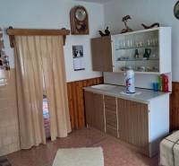 Interior of a family house with a simple kitchen, wooden decor flooring, and curtains.