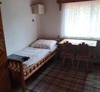 A room in a family house with a bed, a window, a table, and chairs.