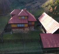 A family house in Zázrivá surrounded by nature, with a red roof and a wooden barn.