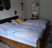 Bedroom in a family house with wooden decor, a large mirror, and wall decorations.