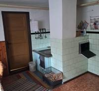 A kitchen in a family house with an antique stove, tiles, and a floor with a wooden decor.