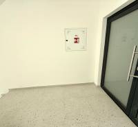 A hallway with glass doors, white walls, and a floor with a white decor in a 2-room apartment.