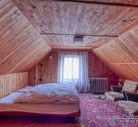 Attic room in a family house with wooden paneling and a decorative carpet.