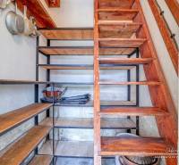 Storage space under the stairs with shelves and kitchen equipment in a family house.