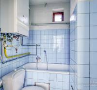 A bathroom in a family house with blue tiles, a bathtub, and a gas boiler.