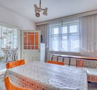 A dining room in a family house with a large window, a floral tablecloth, and orange chairs.