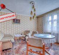 Interior of a family house with vintage furniture, wallpaper, and a large window with a lace curtain.
