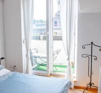 A bedroom in a 3-room apartment with a balcony and a view of the exterior through a French window.