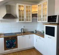 A kitchen in a 3-room apartment with wooden flooring, white cabinets, and storage space.