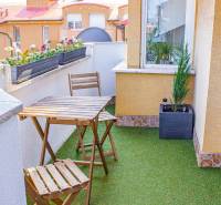 A balcony in a 3-room apartment with seating and plants on artificial grass.