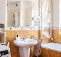 A bathroom in a 3-room apartment with a sink, bathtub, washing machine, and towel rack.