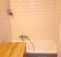 Bathroom in a 2-room apartment with white tiles and a bathtub.