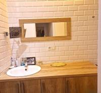 Bathroom in a 2-room apartment with white tiles and wooden decor.