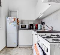 A bright kitchen with white cabinets and appliances in a studio apartment.