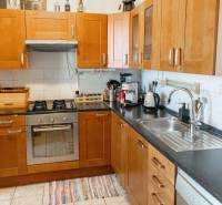 A kitchen in a 2-room apartment with brown cabinets, a stove, and a dishwasher.