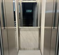 Interior of an elevator with lighting and stainless steel walls.
