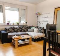 Living room in a two-room apartment with a corner sofa and a floor with a wooden decor.