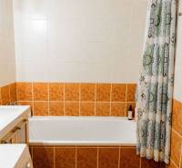 A bathroom with a bathtub and ceramic tiles in a 2-room apartment.