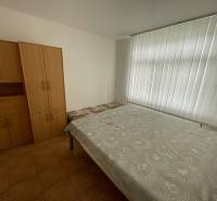 Bedroom in a family house with white blinds, bed, and wardrobes.