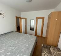 A bedroom with a bed, wardrobe, and mirror in a family house with a wooden decor floor.