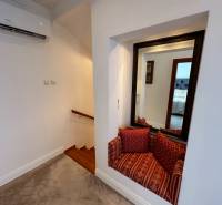 A family house features stairs with a wooden decor, a mirror, and a seating nook with cushions.