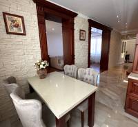 Dining area with a stone wall, white table, and upholstered chairs in a family house.