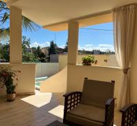 The terrace of a family house in Komárno with seating and a view of the yard with a palm tree.