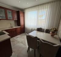 A kitchen with dark cabinets, white curtains, and floral decoration in a family house.