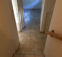 A hallway with tiles leads to a room in a family house with a tiled floor.