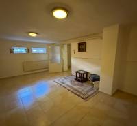 The interior of a family house with tiles, carpet, small windows, and a simple table.