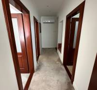 A hallway in a family house with white walls, carpet, and wooden door frames.