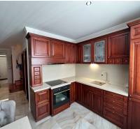 A kitchen with dark wooden cabinets and a wooden decor floor in a family house.