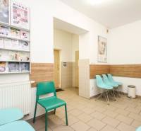 A waiting room with turquoise chairs and magazines, equipped with a wooden decor floor.