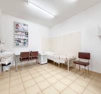 A room in the office with tiles, a sink, chairs, and a couch.