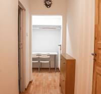 A hallway with a wooden decor floor and white walls in a 2-room apartment.