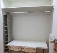 A workspace with a white desk, chairs, and storage shelves in a 2-room apartment.