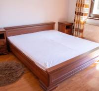 Bedroom with a wooden bed, nightstands, and a floor with a wooden decor in a 2-room apartment.