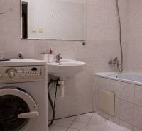 Bathroom in a 2-room apartment with a bathtub, washing machine, and sink.