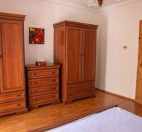 A bedroom with wood-patterned flooring, wardrobes, and a dresser in a two-room apartment.