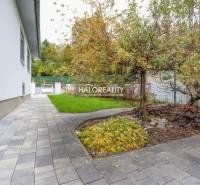 Paving and garden around a family house in Domaniža, with abundant greenery.