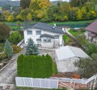 A family house in Domaniža surrounded by greenery, with a driveway and a view of the mountains.