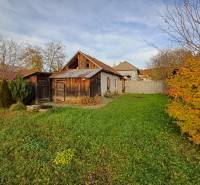 A family house in Dlhá Ves with a garden, wooden extensions, and autumn vegetation.