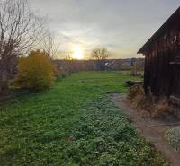 A garden by a family house in Dlhá Ves with a grassy plot and an old wooden structure.