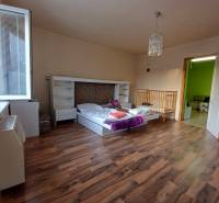 Children's room in a family house with a bed, crib, and floor with wooden decor.