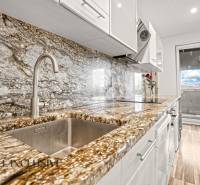 A kitchen with a stone countertop and a wooden decor floor in a 3-room apartment.