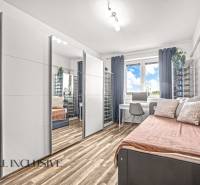 A room with a mirrored wardrobe, a desk, and a floor with a wooden decor in a 3-room apartment.